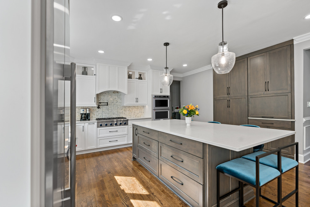Large transitional single-wall kitchen pantry in Dallas with a farmhouse sink, recessed-panel cabinets, white cabinets, quartz benchtops, white splashback, marble splashback, stainless steel appliances, medium hardwood floors, with island, orange floor and white benchtop.
