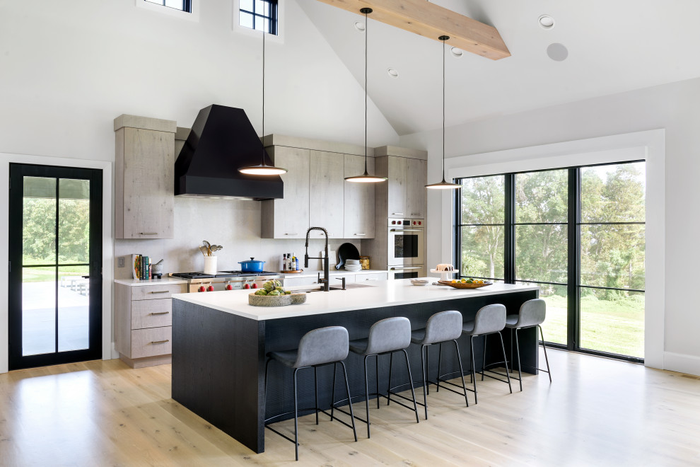 Design ideas for an expansive contemporary single-wall open plan kitchen in New York with an undermount sink, flat-panel cabinets, grey cabinets, quartzite benchtops, grey splashback, stainless steel appliances, light hardwood floors, with island, beige floor, white benchtop, porcelain splashback and vaulted.