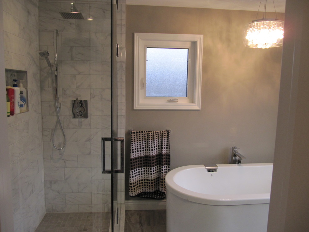 Photo of a large modern master bathroom in Toronto with furniture-like cabinets, a freestanding tub, a corner shower, gray tile, porcelain tile, grey walls, porcelain floors, grey floor and a hinged shower door.
