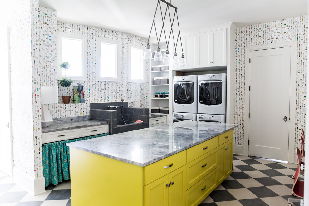 Mid-sized eclectic u-shaped utility room in Salt Lake City with an utility sink, shaker cabinets, yellow cabinets, quartzite benchtops, multi-coloured walls, porcelain floors and a stacked washer and dryer.