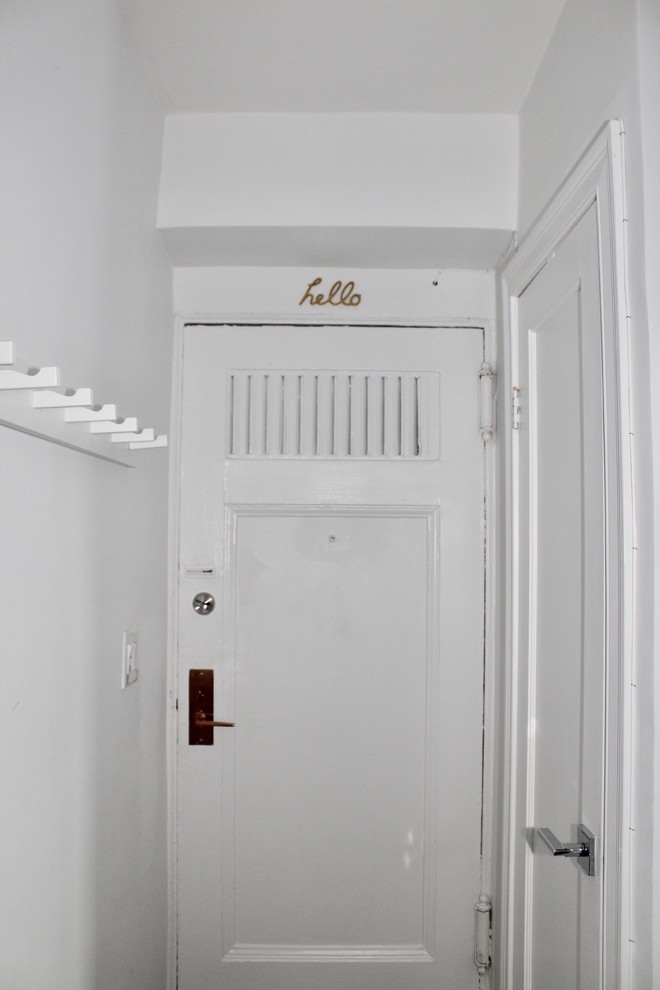This is an example of a small eclectic front door in New York with white walls, dark hardwood floors, a single front door and a white front door.