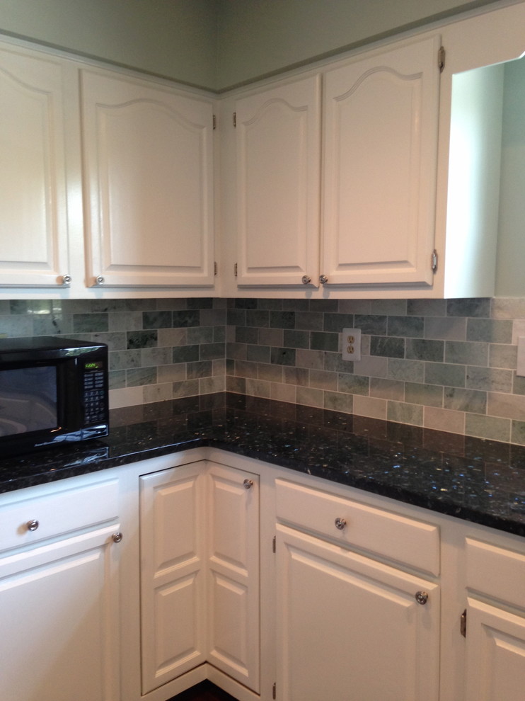 Example of a large transitional u-shaped dark wood floor eat-in kitchen design with a double-bowl sink, raised-panel cabinets, white cabinets, granite countertops, green backsplash, subway tile backsplash, black appliances and a peninsula