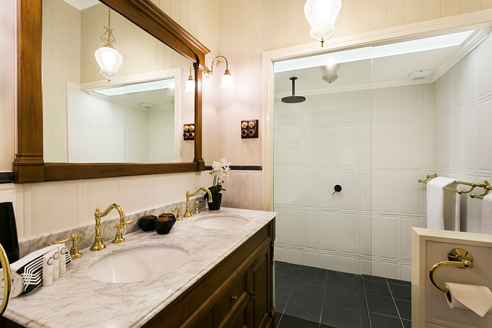 This is an example of a small traditional master bathroom in Brisbane with furniture-like cabinets, medium wood cabinets, an open shower, a one-piece toilet, white tile, ceramic tile, beige walls, a drop-in sink, marble benchtops, an open shower, grey benchtops, a niche, a double vanity, a freestanding vanity, timber, planked wall panelling, cement tiles and black floor.
