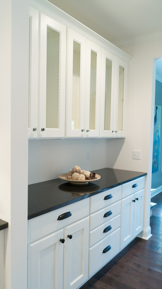 Example of a mid-sized transitional l-shaped dark wood floor open concept kitchen design with an undermount sink, shaker cabinets, white cabinets, granite countertops, gray backsplash, stainless steel appliances and an island