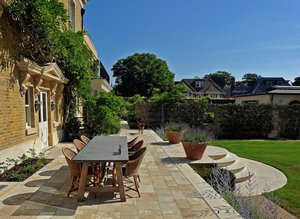 This is an example of a traditional backyard patio in London with no cover.