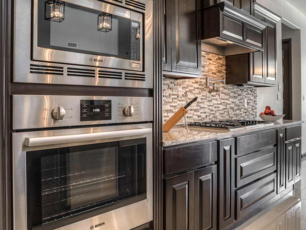 Inspiration for a mid-sized transitional galley marble floor eat-in kitchen remodel in Austin with a farmhouse sink, raised-panel cabinets, dark wood cabinets, granite countertops, brown backsplash, stone tile backsplash and no island