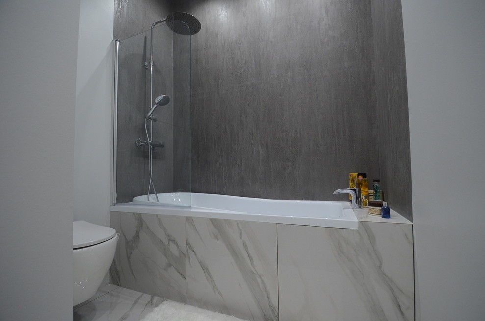 Inspiration for a small contemporary master bathroom in Saint Petersburg with flat-panel cabinets, white cabinets, an alcove tub, a shower/bathtub combo, a wall-mount toilet, gray tile, grey walls, marble floors, white floor and an open shower.