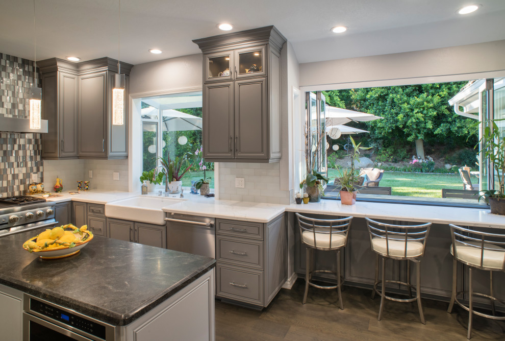 This is an example of a mid-sized modern u-shaped kitchen in Los Angeles with raised-panel cabinets and with island.