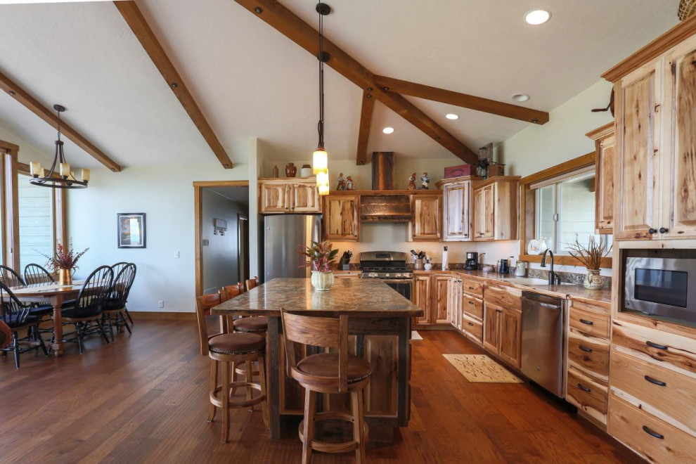 Example of a large mountain style l-shaped medium tone wood floor and brown floor open concept kitchen design with an undermount sink, raised-panel cabinets, medium tone wood cabinets, granite countertops, stainless steel appliances, an island and brown countertops