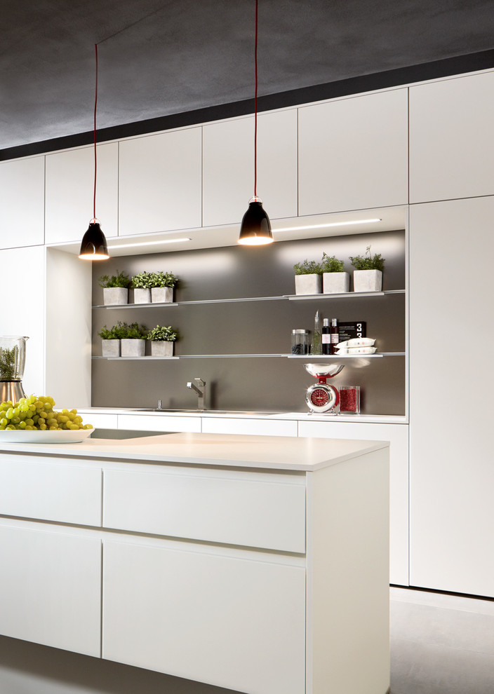 This is an example of a mid-sized contemporary l-shaped eat-in kitchen in Other with a drop-in sink, flat-panel cabinets, laminate benchtops, black appliances, concrete floors and with island.