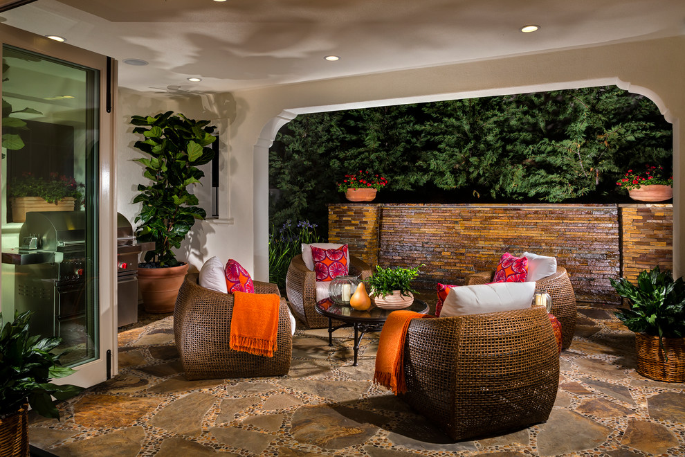 This is an example of a mediterranean patio in Los Angeles with natural stone pavers and a roof extension.