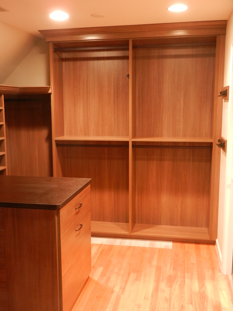 Large traditional gender-neutral walk-in wardrobe in New York with open cabinets, medium wood cabinets and light hardwood floors.