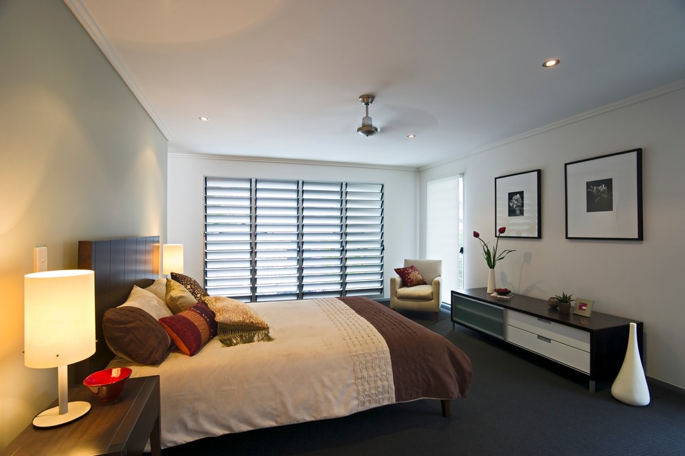 Large contemporary master bedroom in Brisbane with white walls and carpet.