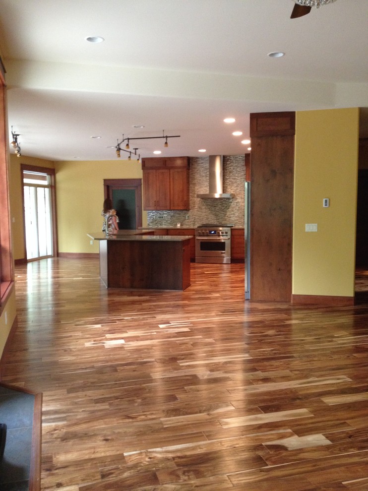Large mountain style l-shaped medium tone wood floor open concept kitchen photo with a farmhouse sink, shaker cabinets, medium tone wood cabinets, granite countertops, multicolored backsplash, matchstick tile backsplash, stainless steel appliances and an island