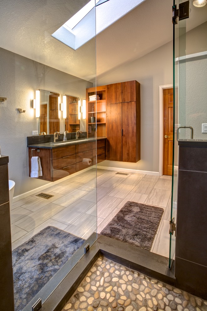 Large transitional master bathroom in Denver with flat-panel cabinets, dark wood cabinets, a freestanding tub, an alcove shower, a two-piece toilet, gray tile, porcelain tile, grey walls, porcelain floors, a trough sink, engineered quartz benchtops, grey floor and a hinged shower door.
