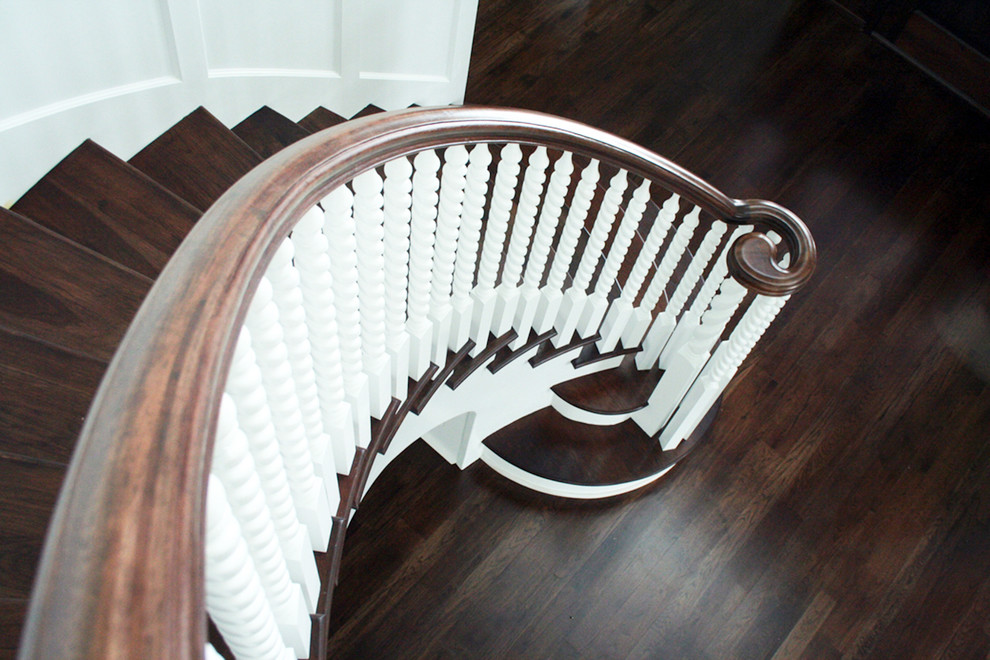 This is an example of a large traditional wood curved staircase in Chicago with wood risers and wood railing.