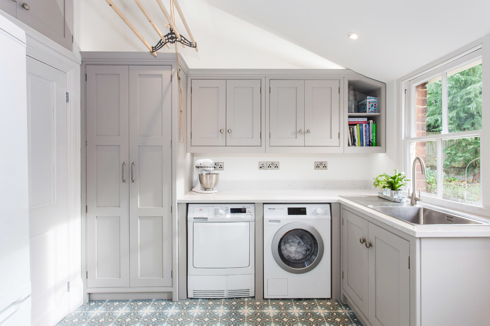 This is an example of a small transitional l-shaped dedicated laundry room in Kent with a single-bowl sink, beaded inset cabinets, grey cabinets, quartzite benchtops, white walls, ceramic floors, a side-by-side washer and dryer and multi-coloured floor.