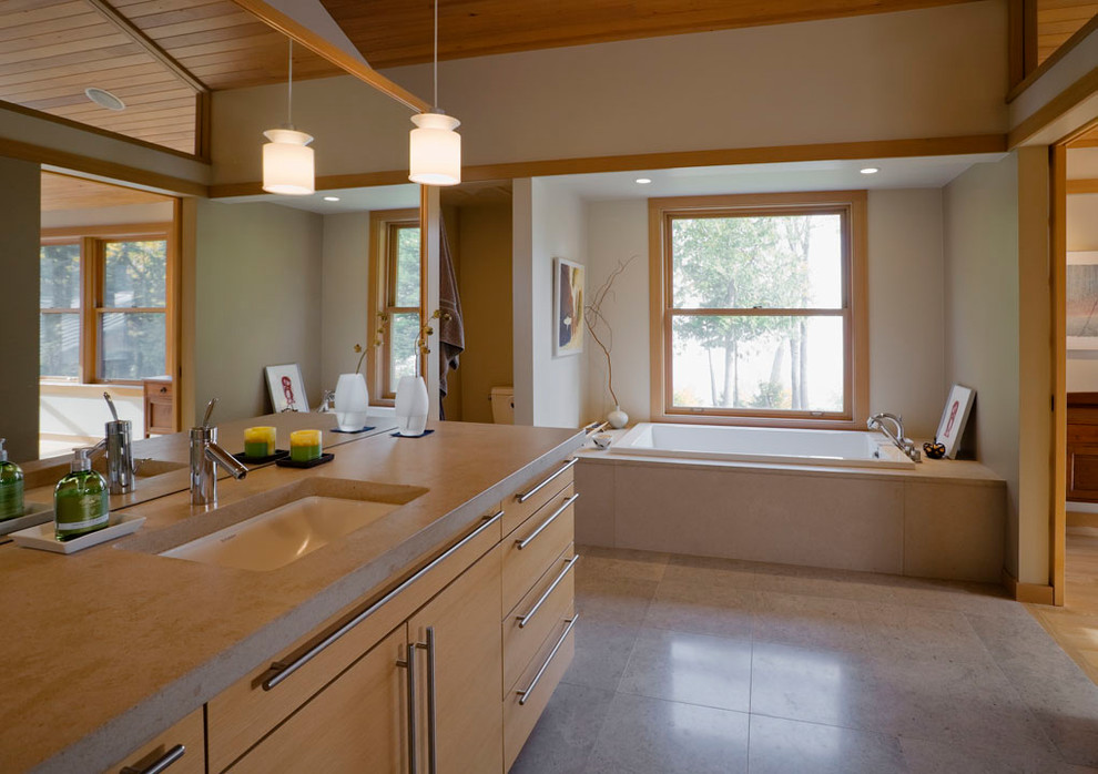 Photo of a large asian master bathroom in Seattle with flat-panel cabinets, light wood cabinets, a drop-in tub, beige walls, an undermount sink, solid surface benchtops and grey floor.