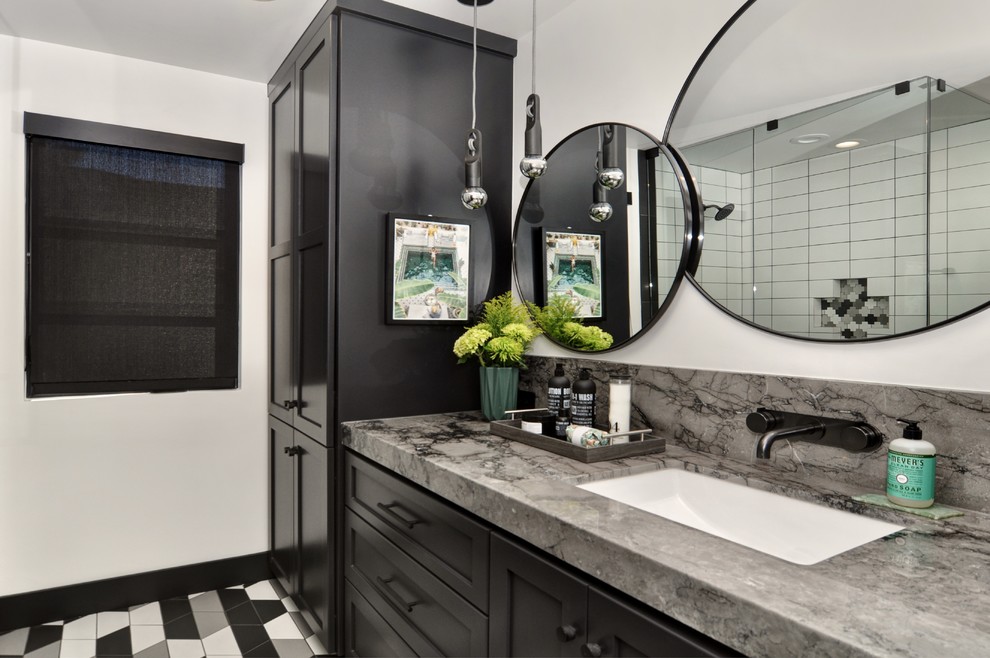 This is an example of a mid-sized transitional kids bathroom in Orange County with shaker cabinets, black cabinets, a one-piece toilet, white tile, ceramic tile, white walls, porcelain floors, an undermount sink, marble benchtops, multi-coloured floor, a hinged shower door and grey benchtops.