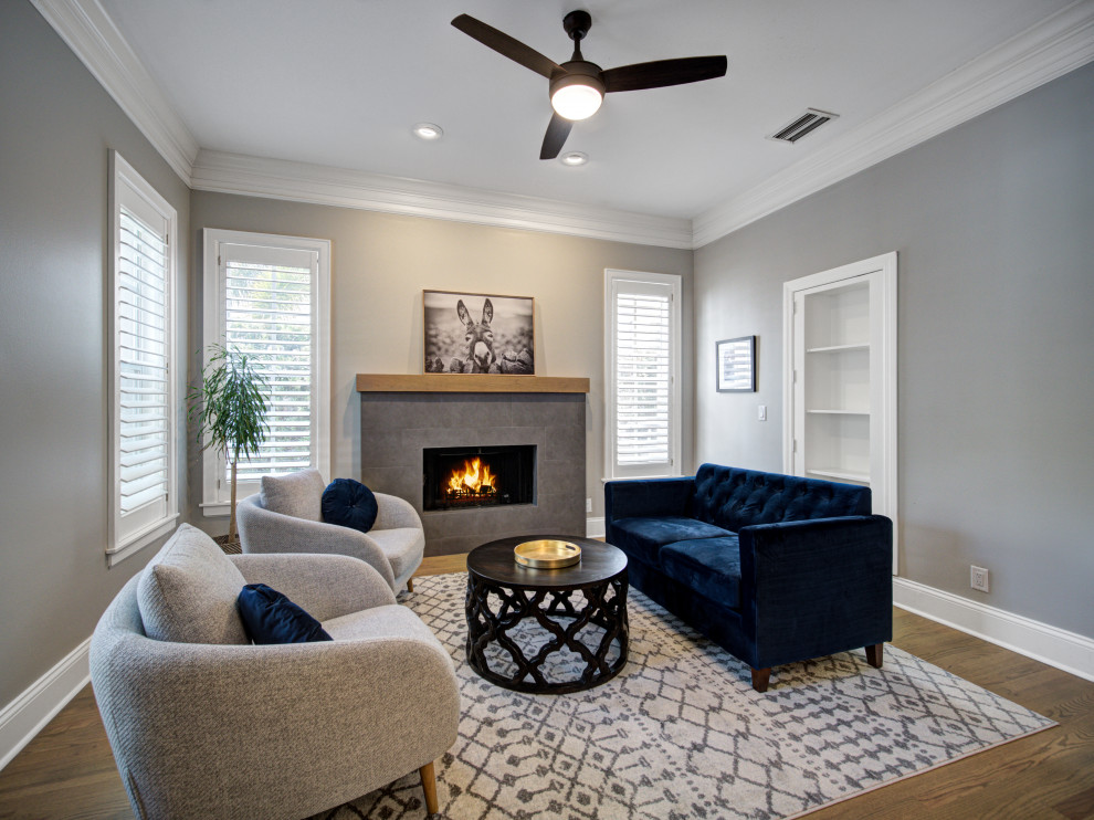 Inspiration for a mid-sized contemporary enclosed family room in Tampa with a library, grey walls, medium hardwood floors, a standard fireplace, a stone fireplace surround, no tv and brown floor.