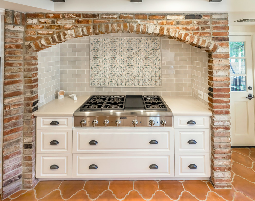 Design ideas for a large mediterranean galley kitchen pantry in Los Angeles with a farmhouse sink, raised-panel cabinets, white cabinets, quartz benchtops, multi-coloured splashback, porcelain splashback, stainless steel appliances, terra-cotta floors, with island and orange floor.