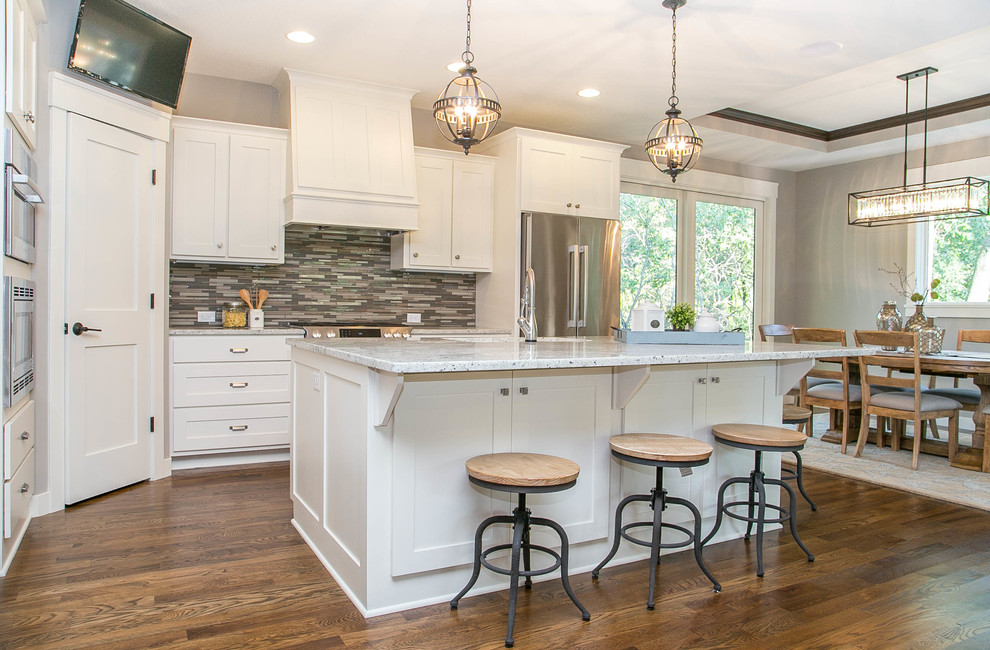 Example of a transitional l-shaped medium tone wood floor eat-in kitchen design in Minneapolis with a drop-in sink, recessed-panel cabinets, white cabinets, granite countertops, multicolored backsplash, glass tile backsplash, stainless steel appliances and an island