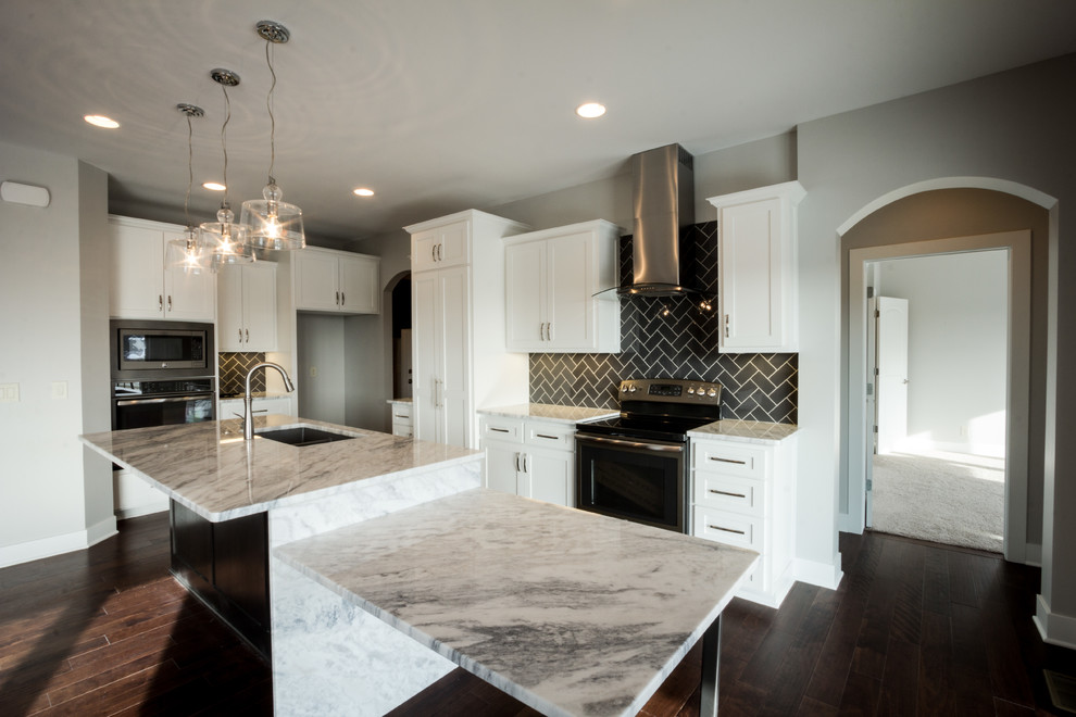 This is an example of a mid-sized modern l-shaped eat-in kitchen in Omaha with an undermount sink, shaker cabinets, white cabinets, granite benchtops, grey splashback, subway tile splashback, stainless steel appliances, dark hardwood floors and with island.