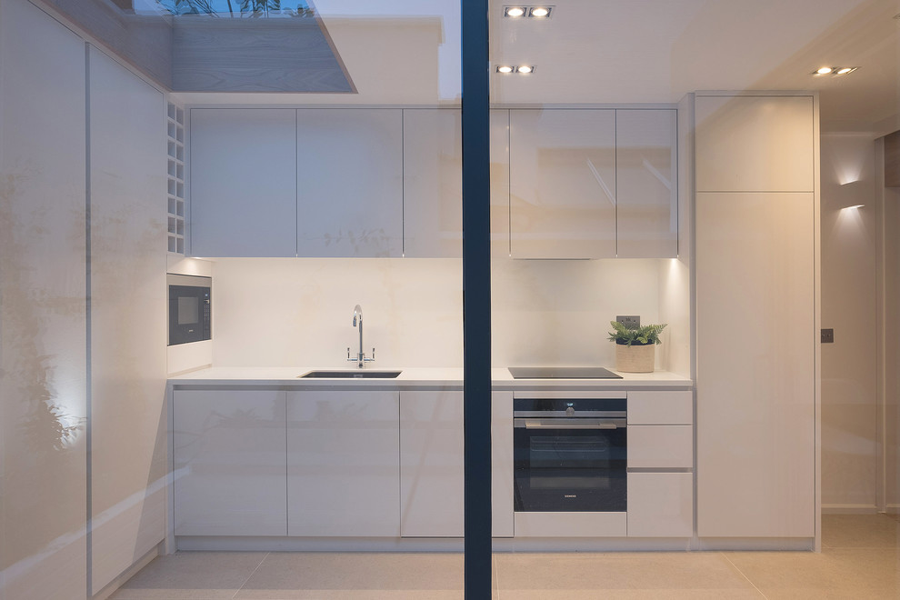 Design ideas for a mid-sized contemporary l-shaped separate kitchen in Essex with an integrated sink, flat-panel cabinets, yellow cabinets, solid surface benchtops, white splashback, panelled appliances, ceramic floors, no island and beige floor.