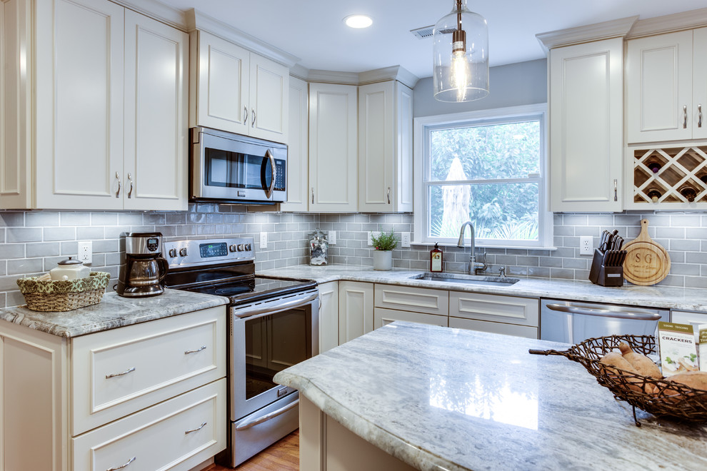This is an example of a mid-sized traditional u-shaped kitchen in DC Metro with an undermount sink, granite benchtops, grey splashback, stainless steel appliances, medium hardwood floors and with island.