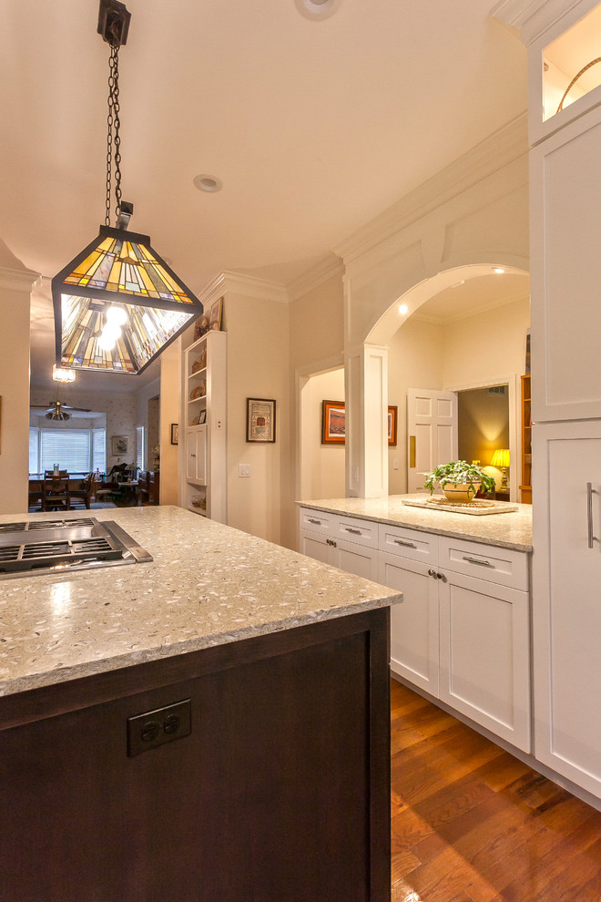 This is an example of an expansive traditional u-shaped eat-in kitchen in Charleston with with island, recessed-panel cabinets, white cabinets, recycled glass benchtops, an undermount sink, white splashback, ceramic splashback, stainless steel appliances, medium hardwood floors and beige floor.