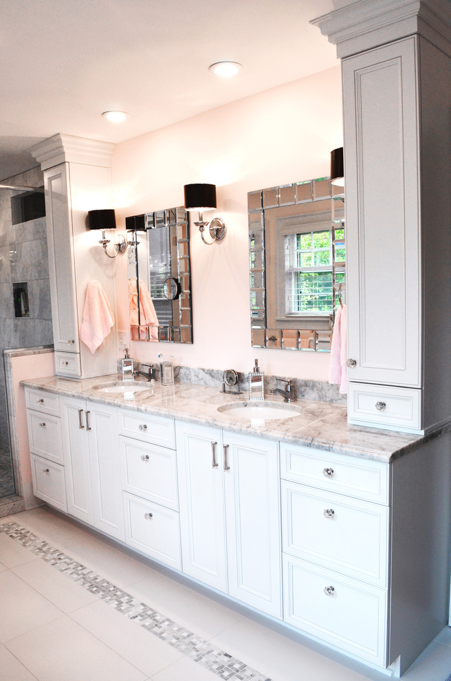 Photo of a mid-sized traditional master bathroom in Seattle with recessed-panel cabinets, white cabinets, a corner shower, a one-piece toilet, white tile, pink walls, porcelain floors, an undermount sink and marble benchtops.