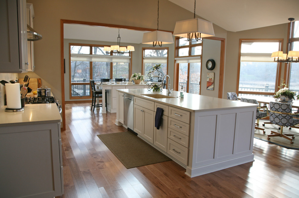 Large beach style light wood floor, brown floor and vaulted ceiling eat-in kitchen photo in Milwaukee with an undermount sink, shaker cabinets, white cabinets, quartz countertops, white backsplash, porcelain backsplash, stainless steel appliances, two islands and white countertops