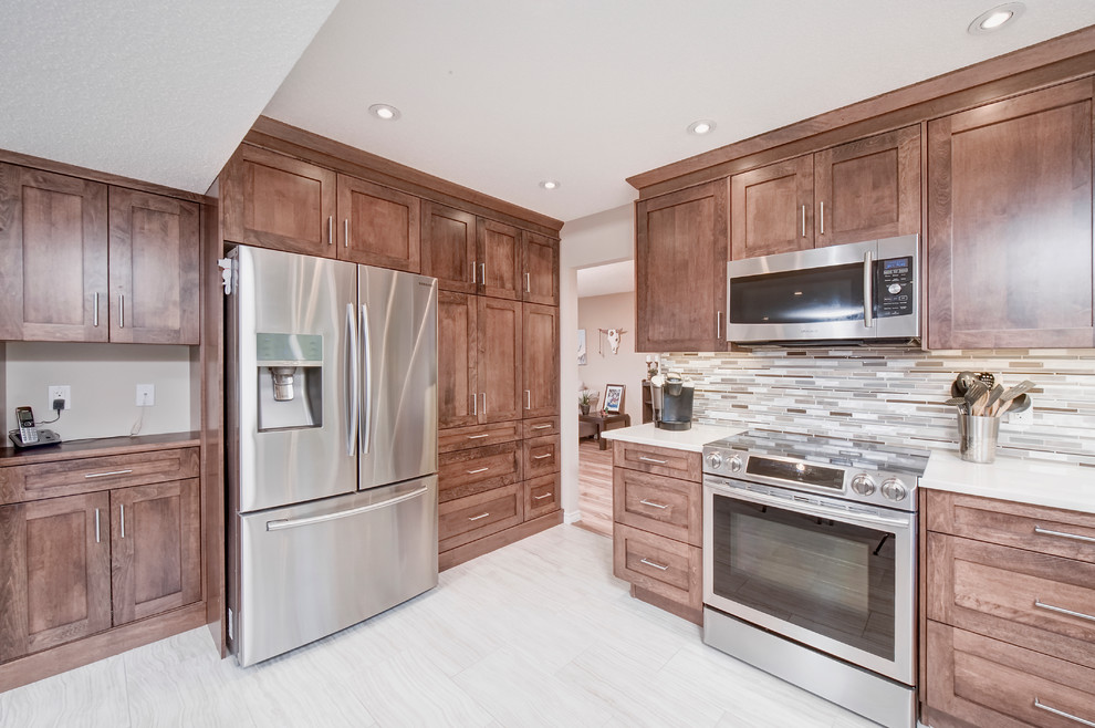 Eat-in kitchen - mid-sized transitional l-shaped porcelain tile and beige floor eat-in kitchen idea in Calgary with an undermount sink, shaker cabinets, medium tone wood cabinets, quartz countertops, multicolored backsplash, mosaic tile backsplash, stainless steel appliances and no island