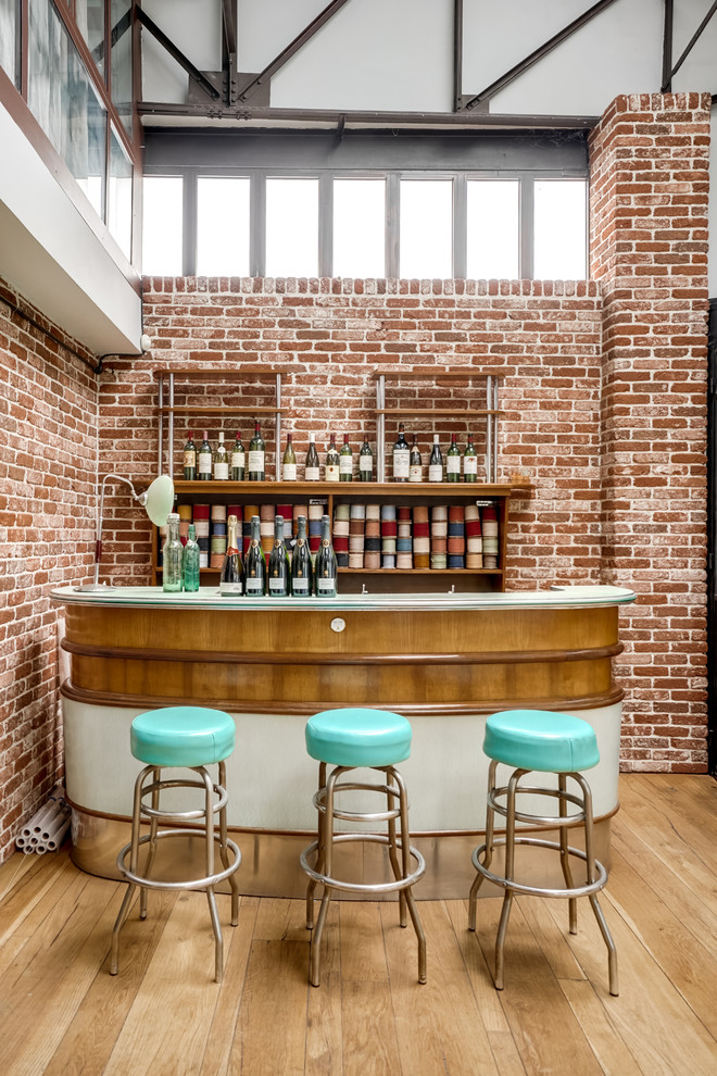 Inspiration for a large industrial single-wall seated home bar in Paris with open cabinets, beige floor, medium wood cabinets, light hardwood floors and white benchtop.