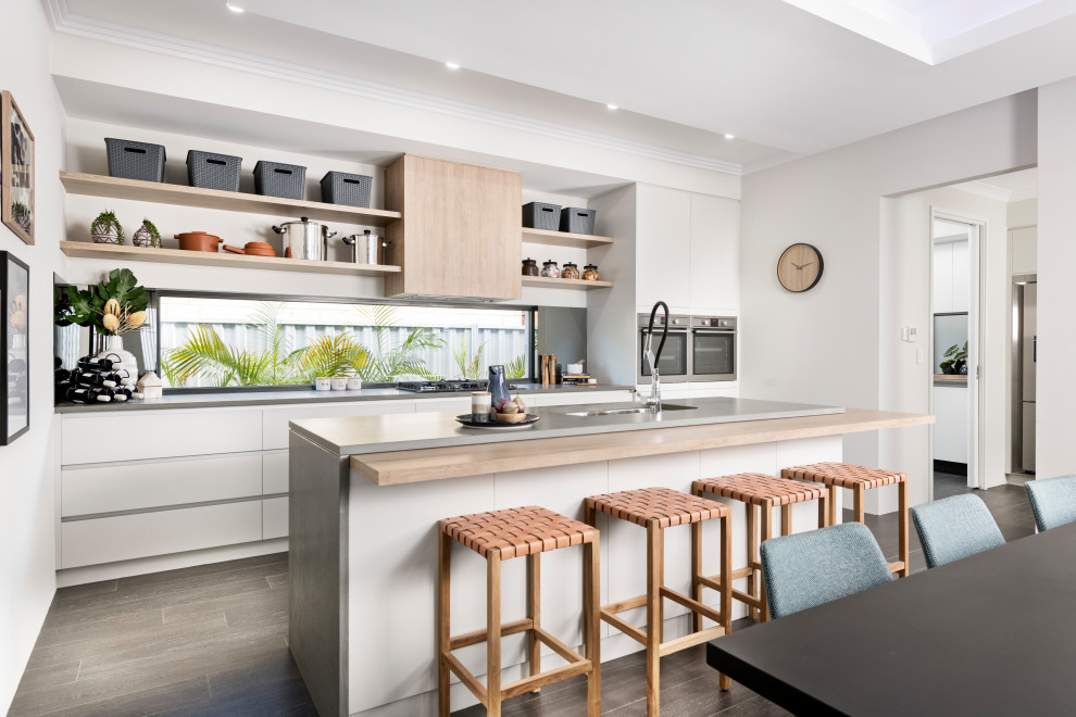 Design ideas for a mid-sized contemporary galley kitchen in Perth with an undermount sink, flat-panel cabinets, white cabinets, mirror splashback, stainless steel appliances, with island, grey floor and grey benchtop.