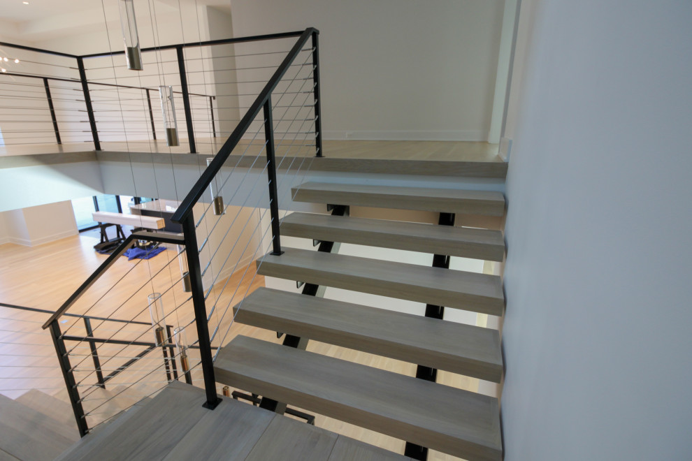 Стильный дизайн: большая лестница на больцах в стиле фьюжн с деревянными ступенями, металлическими перилами и кирпичными стенами - последний тренд