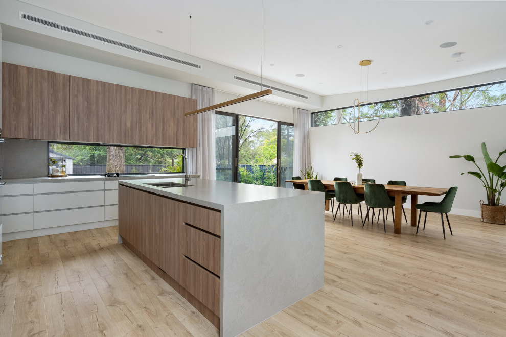 Foto di una sala da pranzo aperta verso la cucina contemporanea con pavimento in laminato e pavimento marrone