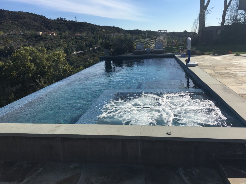 Inspiration for a medium sized farmhouse back rectangular infinity swimming pool in Los Angeles with tiled flooring.