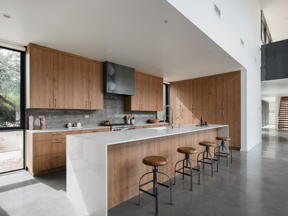 Foto di una cucina minimalista con ante lisce, ante in legno scuro, top in quarzo composito, paraspruzzi grigio, pavimento in cemento e top bianco