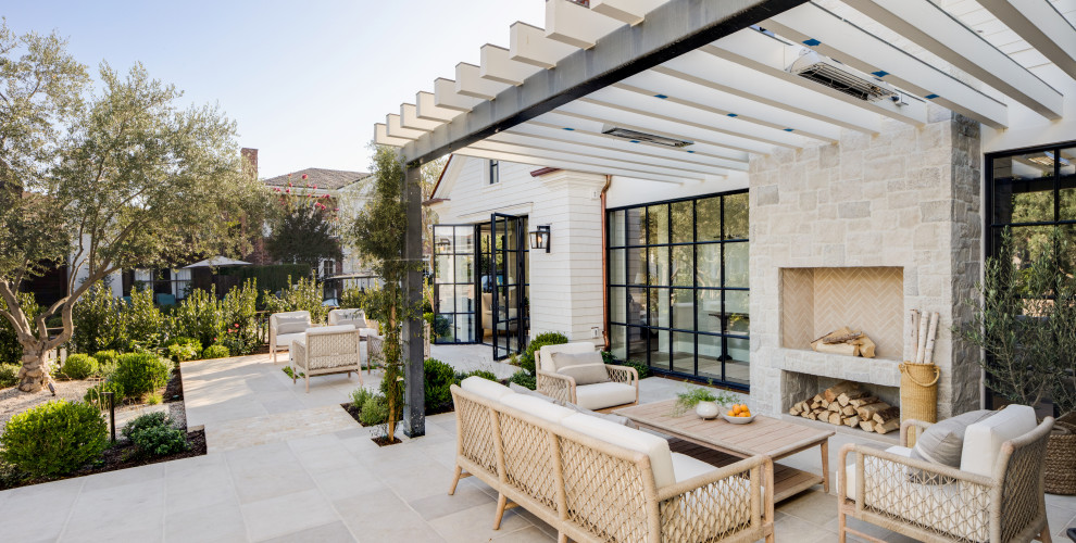 Coastal patio in Los Angeles with a fireplace, tiled flooring and a pergola.
