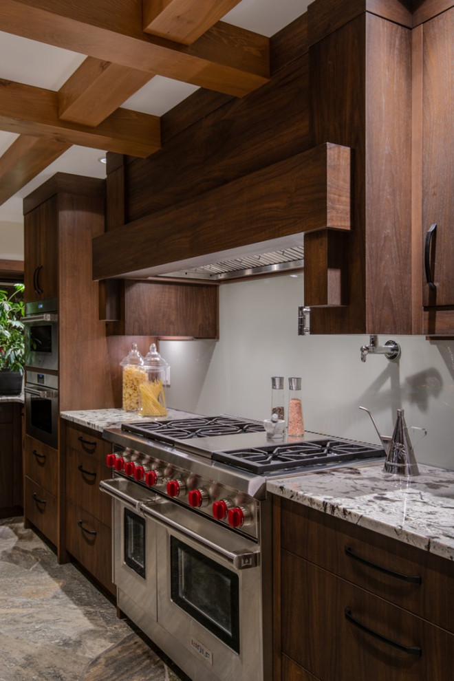 Inspiration for a mid-sized transitional u-shaped kitchen in Vancouver with a double-bowl sink, flat-panel cabinets, medium wood cabinets, granite benchtops, white splashback, glass sheet splashback, stainless steel appliances, slate floors, with island and grey floor.