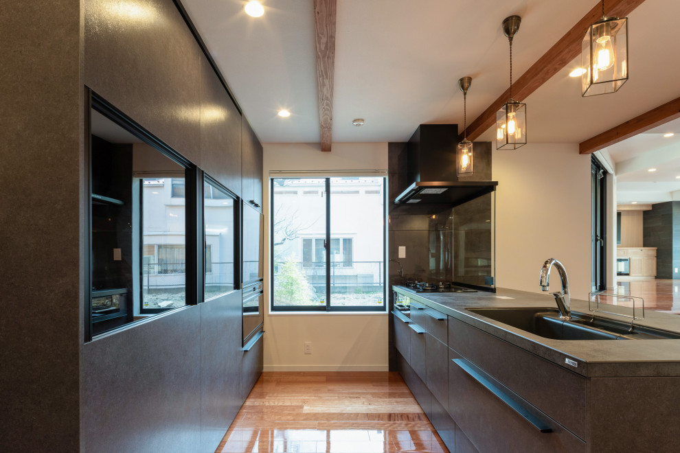 Immagine di una grande cucina minimalista con ante lisce, ante con finitura invecchiata, elettrodomestici neri, pavimento in legno massello medio, pavimento marrone, top nero e soffitto in carta da parati