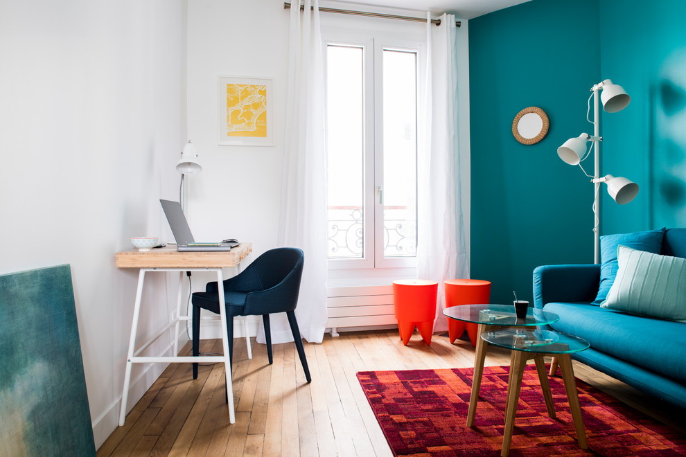 This is an example of a small eclectic home office in Paris with blue walls, no fireplace, dark hardwood floors, a freestanding desk and brown floor.