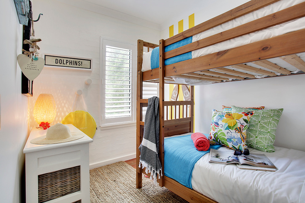 This is an example of a beach style gender-neutral kids' room in Sydney with white walls and light hardwood floors.