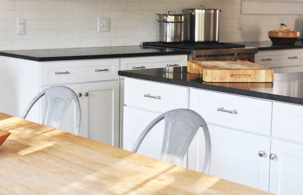 Home design - mid-sized transitional l-shaped medium tone wood floor home design idea in Richmond with a farmhouse sink, shaker cabinets, white cabinets, granite countertops, white backsplash, subway tile backsplash and stainless steel appliances