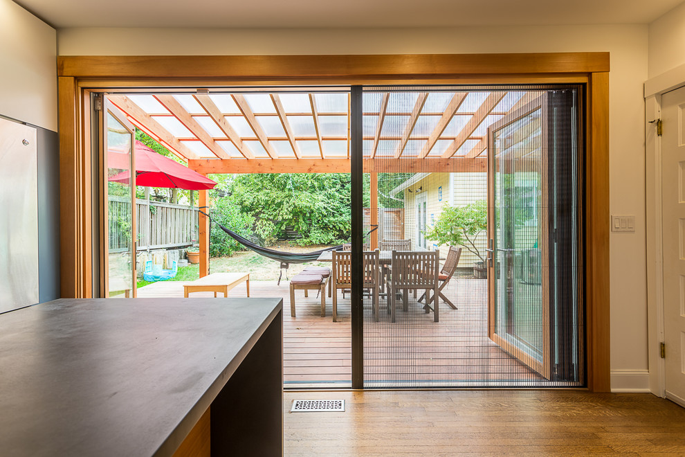 This is an example of a mid-sized contemporary backyard patio in Portland with decking and a roof extension.
