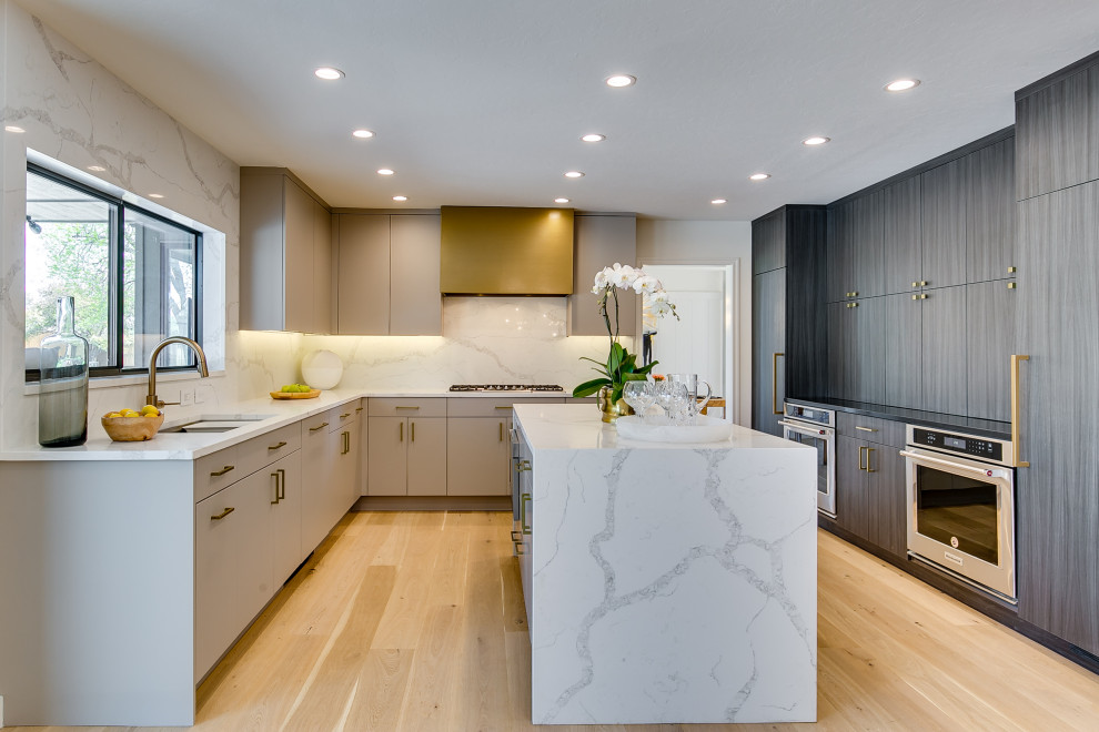 Photo of a contemporary u-shaped kitchen in Oklahoma City with an undermount sink, flat-panel cabinets, grey cabinets, white splashback, stainless steel appliances, light hardwood floors, with island, beige floor and white benchtop.