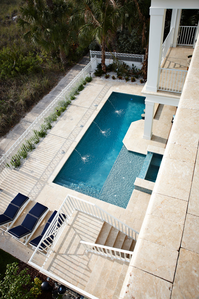 Photo of a small contemporary backyard rectangular lap pool in Tampa with a water feature and natural stone pavers.