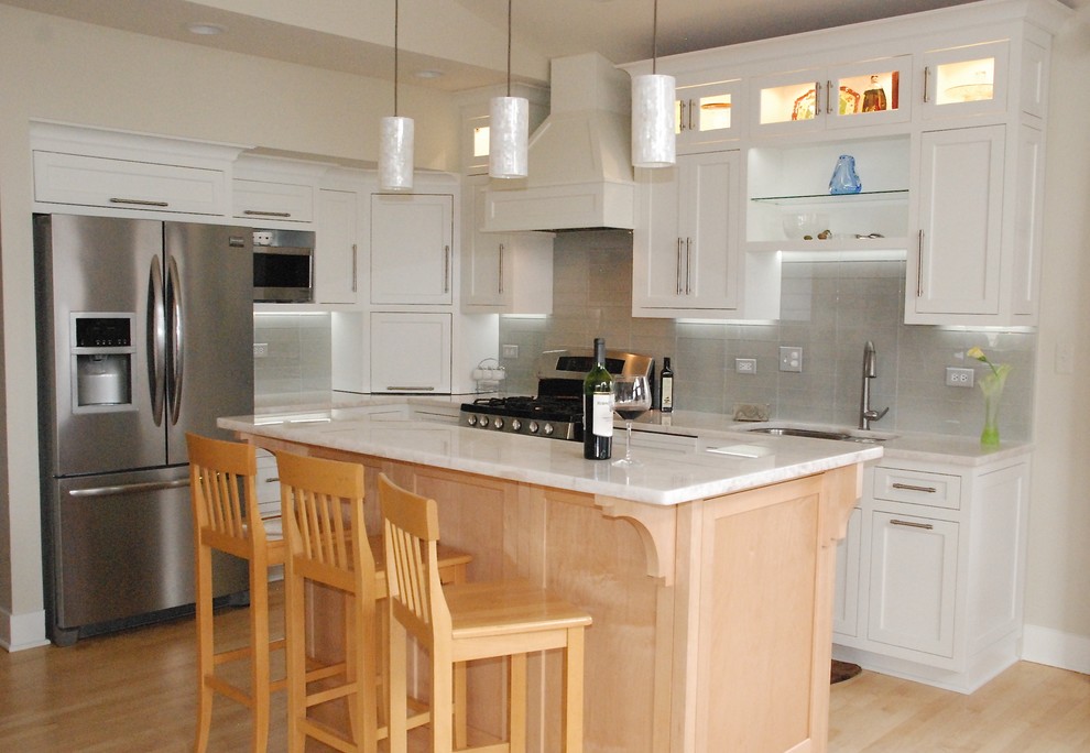Inspiration for a small transitional l-shaped light wood floor eat-in kitchen remodel in Chicago with a double-bowl sink, recessed-panel cabinets, white cabinets, quartzite countertops, gray backsplash, glass tile backsplash, stainless steel appliances and an island