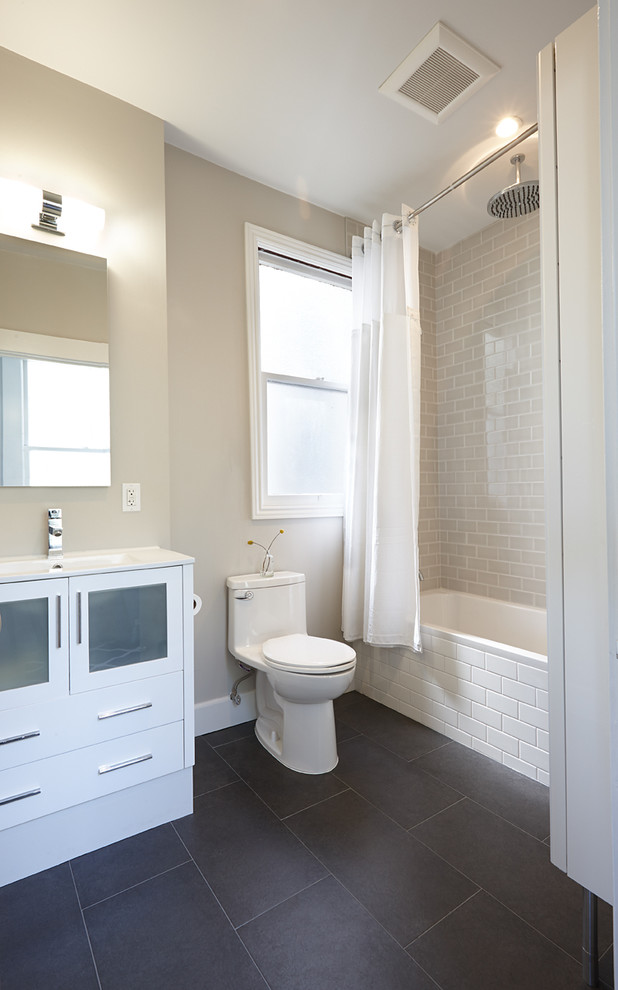 Inspiration for a transitional bathroom in San Francisco with glass-front cabinets, white cabinets, an alcove tub, a shower/bathtub combo, a one-piece toilet, beige tile, beige walls and black floor.